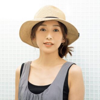 リゾートスタイルに寄り添うつば広の麦わら帽子には、サイドに寄せたラフなシニヨンが好相性。