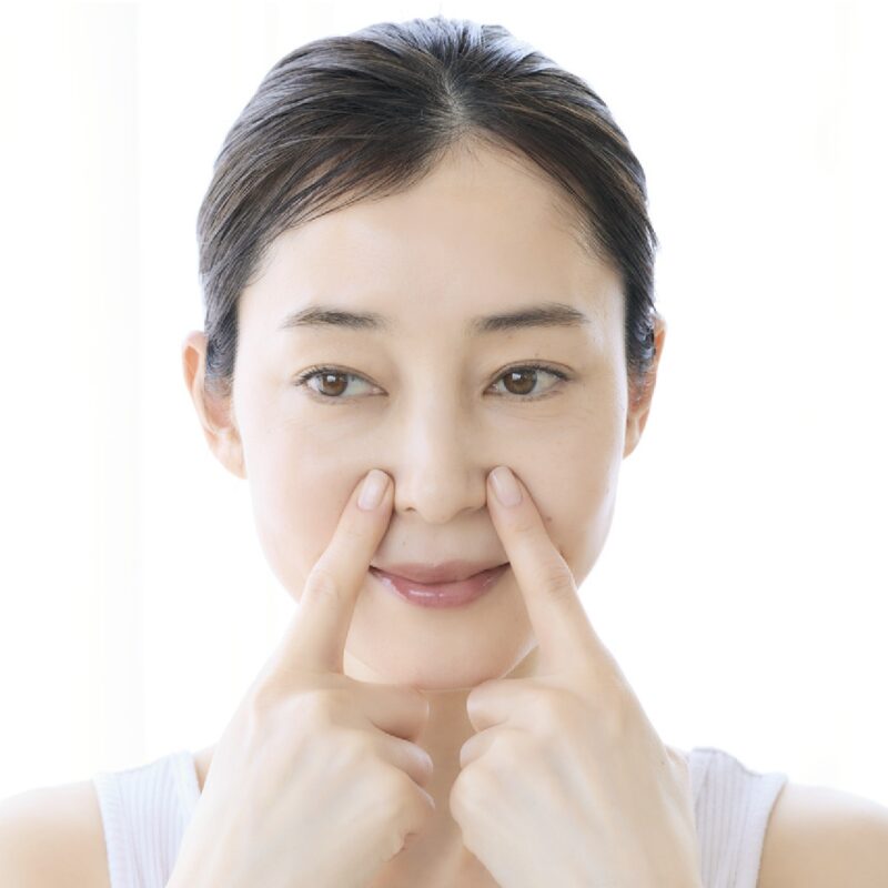 鼻の横のツボを押す