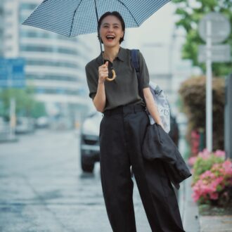 パンツ4万8400円、ポロニット3万800円（ともにハイク／ボウルズ） 手に持ったジャケット1万8700円（カランシエル／シップス インフォメーションセンター） バックパック2万3100円（アコック／ジャック・オブ・オール・トレーズ プレスルーム） 靴4万1800円（プレインピープル／プレインピープル青山） 傘1万5400円（トラディショナル ウェザーウェア／トラディショナル ウェザーウェア ルミネ有楽町店）