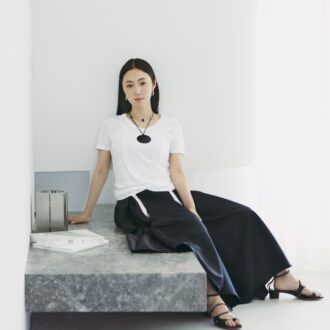 Tシャツ8800円（ミースロエ／MIESROHE ルミネ新宿1店）　中に来たガータータンク7480円（オーバーニース）、ピアス4万6200円（エルエルシー／ともにザニーム）　スカート5万5000円（サードマガジン）　チョーカー13万2000円（アサミ フジカワ／ショールーム セッション）　コードネックレス21万8900円（ソフィー ブハイ／エスケーパーズ アナザーワールド）　サンダル5万600円（カチム）