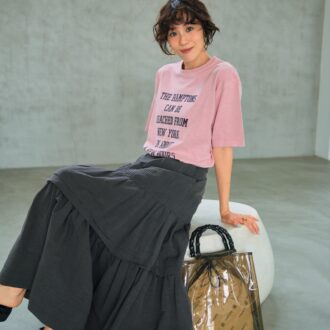 グレージュのティアードスカー トでシックに。Tシャツのタイポ グラフィーもグレージュのもの を選んで、さらにすっきりと洗練 された着こなしに。Tシャツ64 90円（デッサン／ワールド プレ スインフォメーション） スカー ト7万7000円（オブリオ） バッ グ1万6500円（ピモンテ） サン ダル1万8150円（ダイアナ／ダ イアナ 銀座本店） イヤリング 4950円（MU）、リング2530円 （シースキー／ともにロードス）
