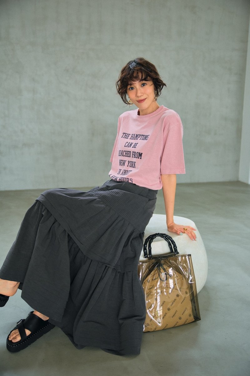 グレージュのティアードスカー トでシックに。Tシャツのタイポ グラフィーもグレージュのもの を選んで、さらにすっきりと洗練 された着こなしに。Tシャツ64 90円（デッサン／ワールド プレ スインフォメーション） スカー ト7万7000円（オブリオ） バッ グ1万6500円（ピモンテ） サン ダル1万8150円（ダイアナ／ダ イアナ 銀座本店） イヤリング 4950円（MU）、リング2530円 （シースキー／ともにロードス）
