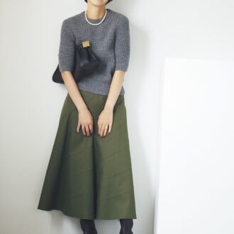 クラシックな気品を醸し出すフレアスカートで、カーキをレディなムードにシフトチェンジ。プレーンなニットとパールネックレスで清楚な華やかさを投入。あえて黒の小物でクールに。ニット3万5200円（オブリオ）　スカート4万2900円（ミュベール）　ネックレス3万8500円（リューク）　バッグ6万6000円（トラモンターノ／ピモンテ）　ショートブーツ3万30 00円（ダニエラアンドジェマ）
