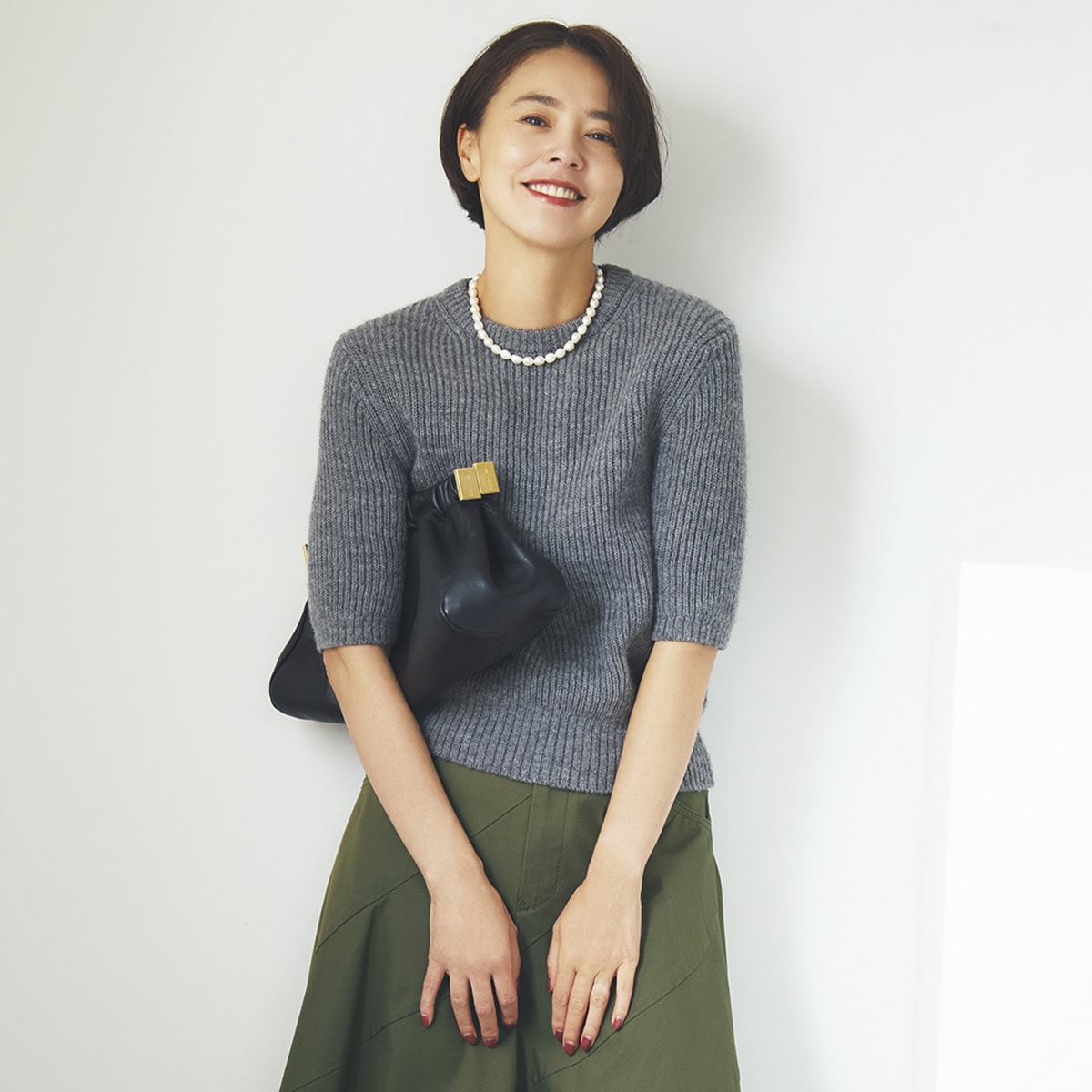 クラシックな気品を醸し出すフレアスカートで、カーキをレディなムードにシフトチェンジ。プレーンなニットとパールネックレスで清楚な華やかさを投入。あえて黒の小物でクールに。ニット3万5200円（オブリオ）　スカート4万2900円（ミュベール）　ネックレス3万8500円（リューク）　バッグ6万6000円（トラモンターノ／ピモンテ）　