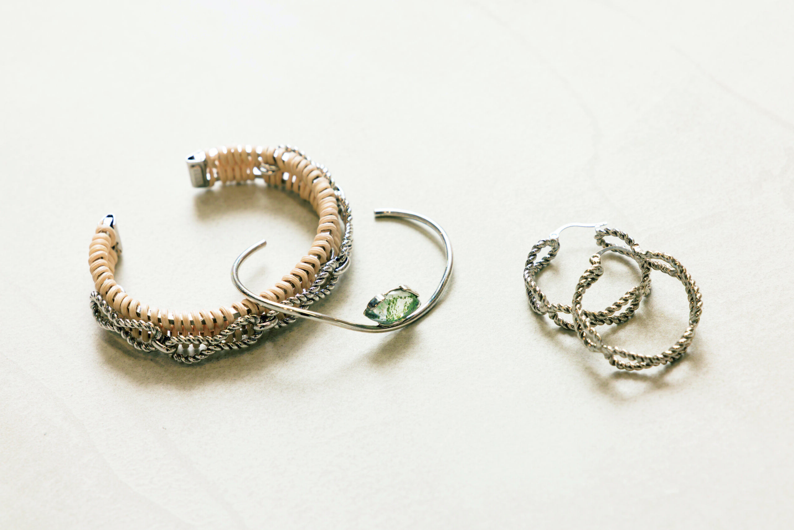 アデル ビジューのツイストピアス。シルバーカラーやラタンのバングル